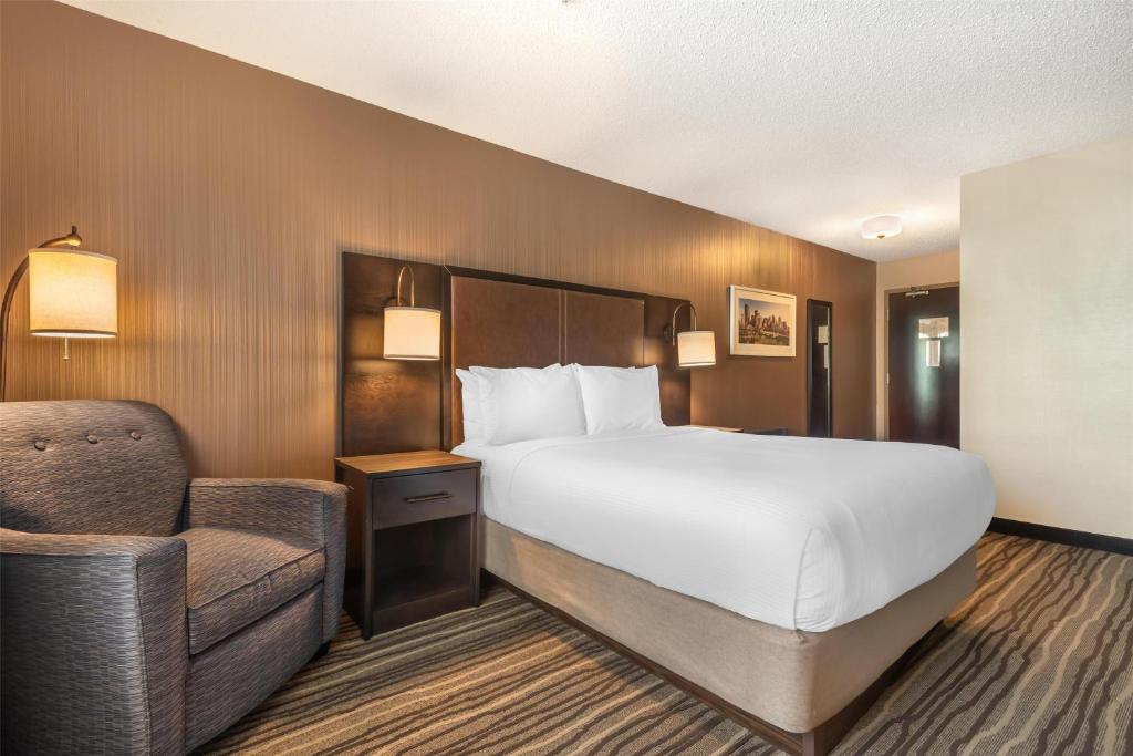 a hotel room with a bed and a chair at Best Western PLUS Calgary Centre Inn in Calgary