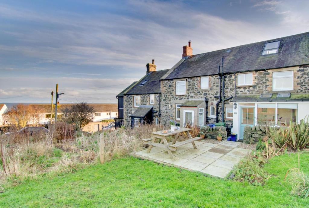 a stone house with a picnic table in front of it at Castle Point Cottage Craster in Craster