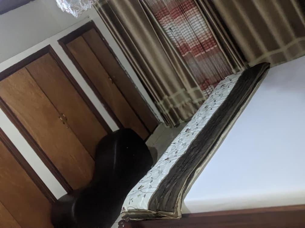 un chat noir assis sur un lit regardant par la fenêtre dans l'établissement Motel, à Kigali