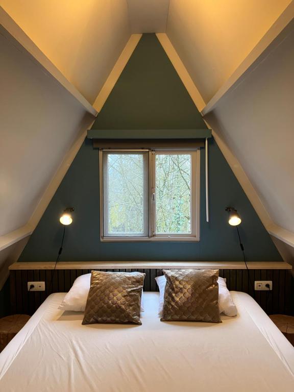 a bedroom with a large bed with a window at Chalet Tournesol Durbuy in Durbuy