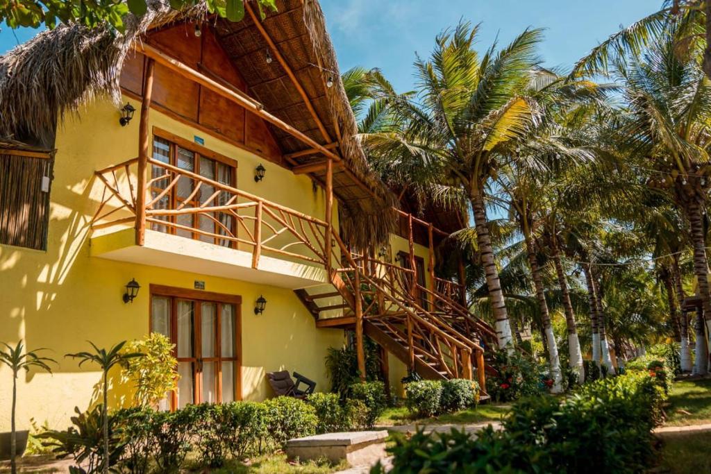 a yellow building with a balcony and palm trees at Waikiki Beach Boutique Hostel in Dibulla