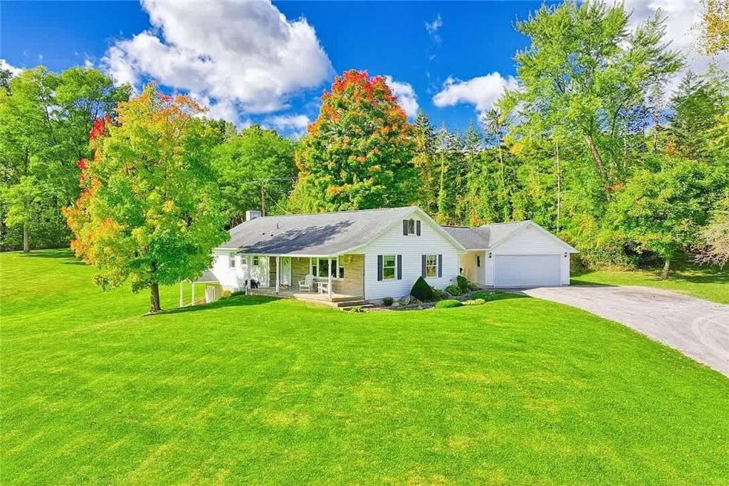 a white house on a green yard with a driveway at High-End Finger Lakes Escape - Expansive Game Room, Cozy Firepit, & Scenic Views in Penn Yan