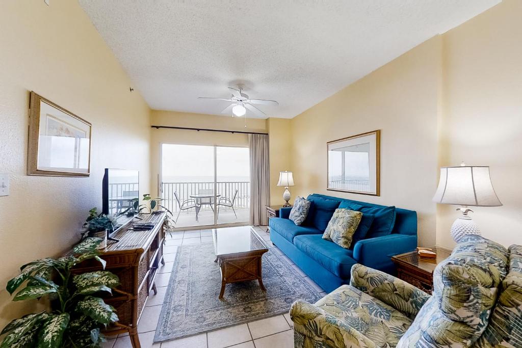 Una sala de estar con un sofá azul y una mesa. en Tidewater 608, en Orange Beach