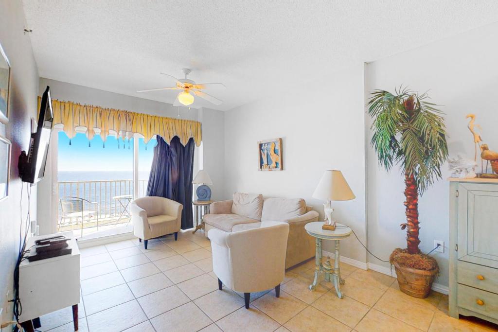 Una sala de estar con un sofá y una palmera. en Tidewater 908, en Orange Beach