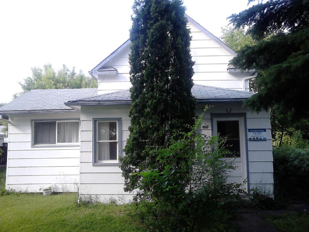 a tree in front of a white house at Canora Vacation Home in Canora