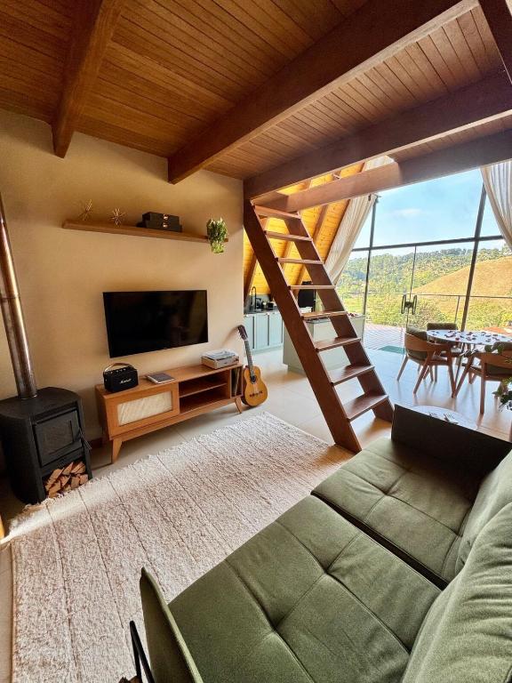 a living room with a couch and a tv and a staircase at Chalé Encanto de Maria em Teresópolis in Teresópolis