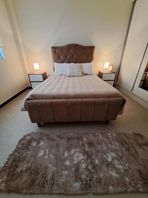 ein Schlafzimmer mit einem großen Bett und zwei Tischen mit Lampen in der Unterkunft Cómodo departamento en barrio petrolero in Sucre