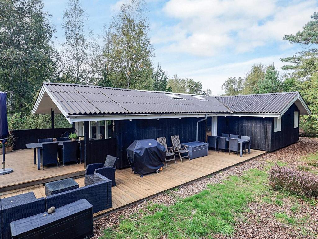 una casa con terraza con mesa y sillas en 6 person holiday home in Ålbæk, en Ålbæk