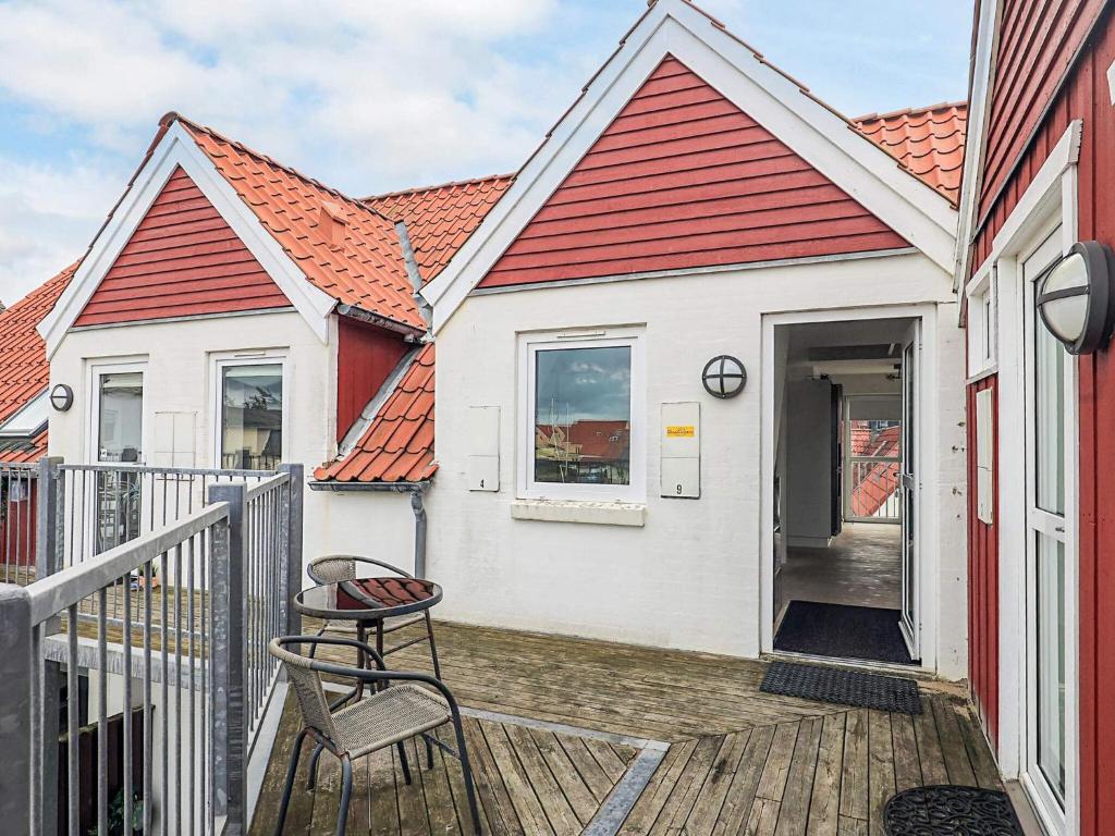 een wit huis met een rood dak en een krukje op een terras bij 5 star holiday home in Løkken in Løkken