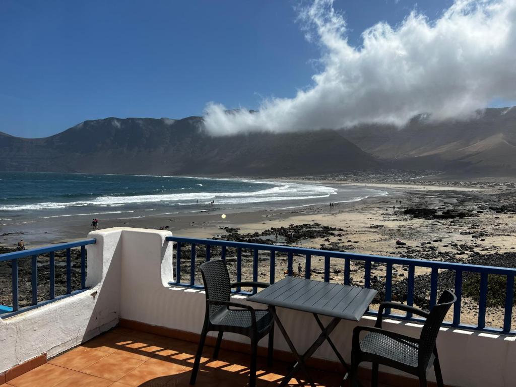 a table and chairs on a balcony with a beach at Playa de Caleta de Famara in Famara