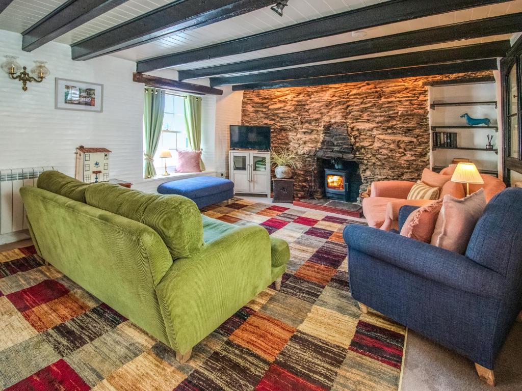 a living room with two chairs and a fireplace at Charlie Wilcox Cottage in Polperro