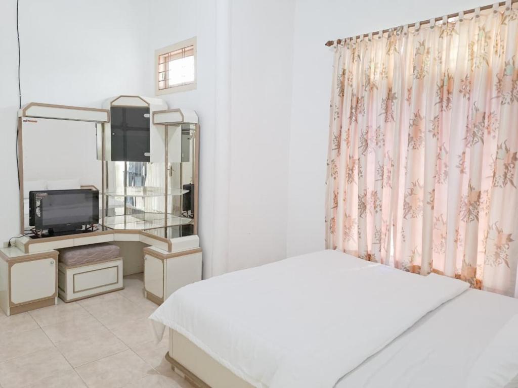 a bedroom with a bed and a mirror and a television at MAWAR Guest House By Hans Management in Bandar Lampung