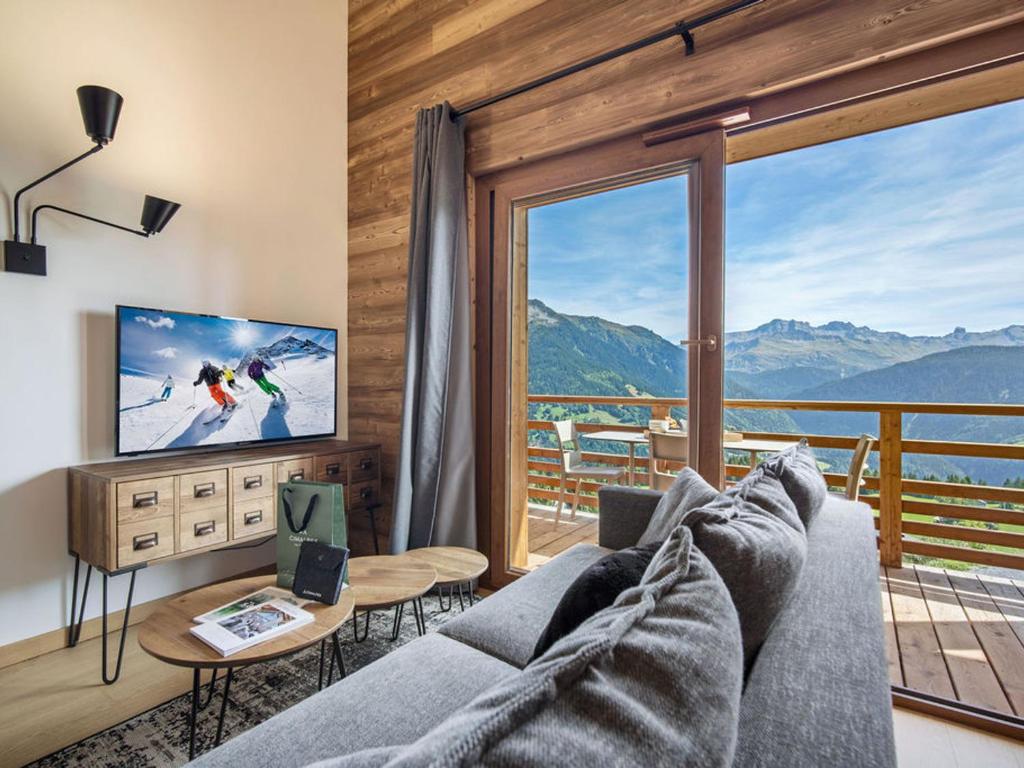 a living room with a couch and a large window at Appartement T2 confort 4 pers., parking inclus - FR-1-809-29 in Les Saisies