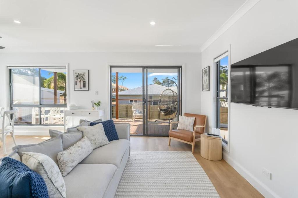 a white living room with a couch and chairs at Bay Breeze Beachhouse in Scarness