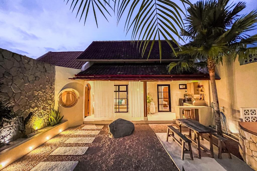 a house with a bench and a palm tree at Ubu Villa Lemme with Rustic Mediterranean Style in Adi Sutjipto