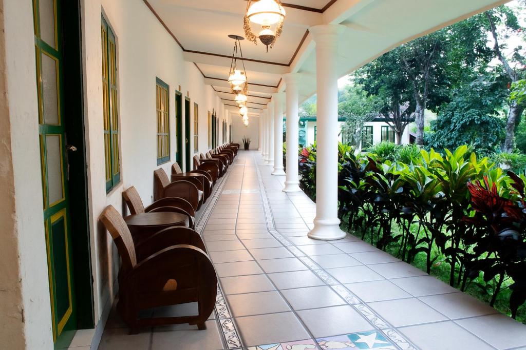 a corridor of a building with benches and plants at Omah Kebon Guest House in Temanggung