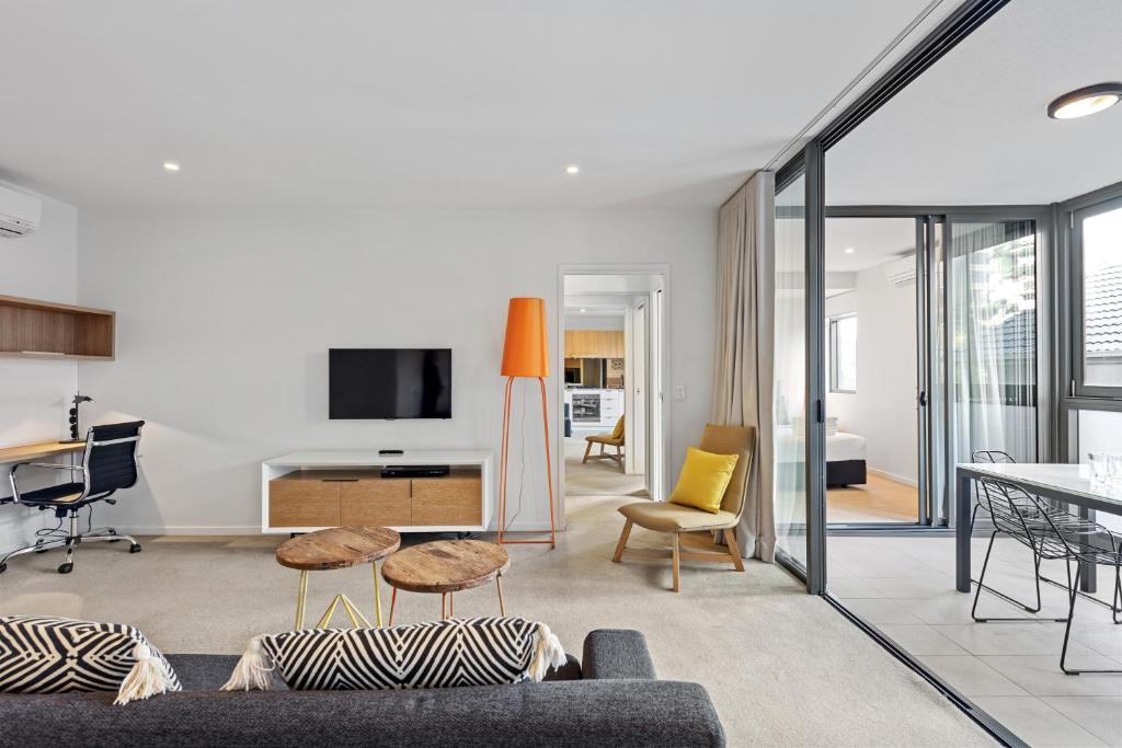 a living room with a couch and a tv at Vine Apartments South Brisbane in Brisbane
