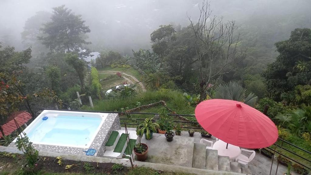 a red umbrella next to a swimming pool with aitating at Manaju - Finca Campestre y Glamping in Ibagué