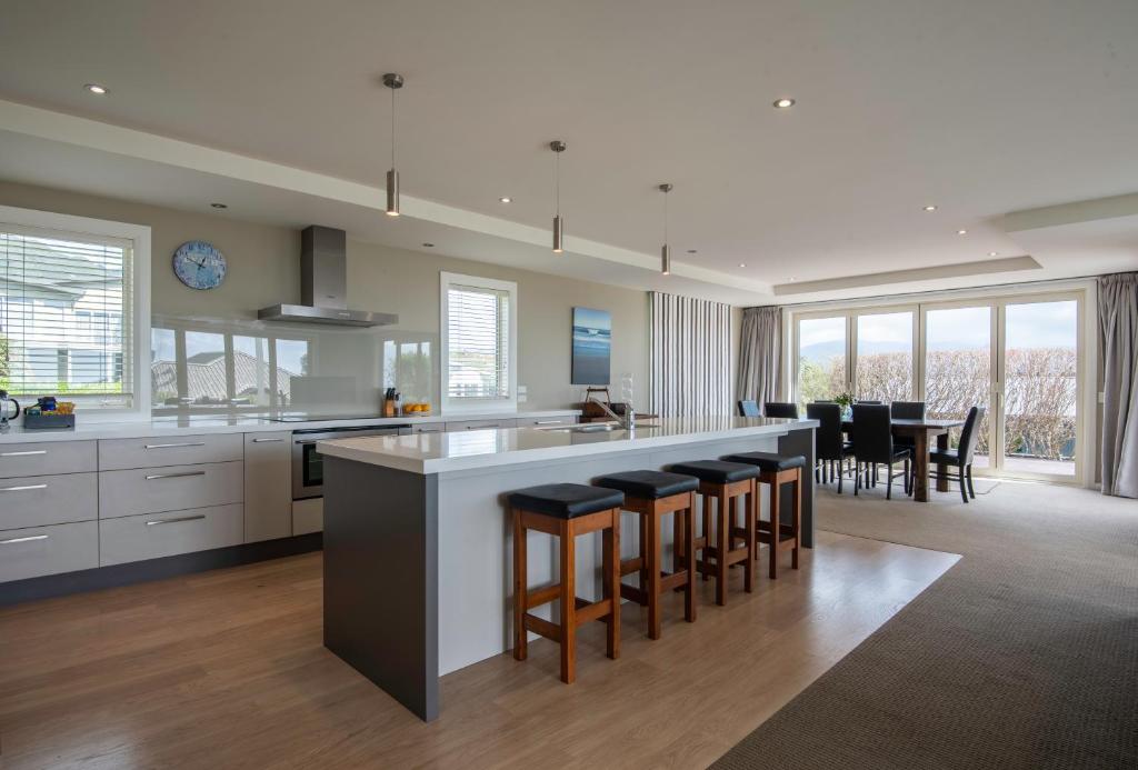 a kitchen with a bar with stools and a dining room at Pohara Heights Executive Holiday Home in Pohara