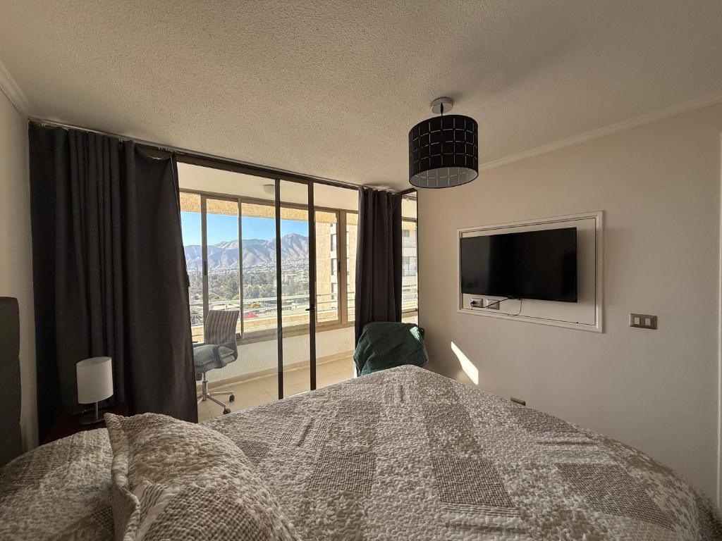 a bedroom with a bed and a tv and a window at Hermoso Departamento en edificio Innova in Copiapó
