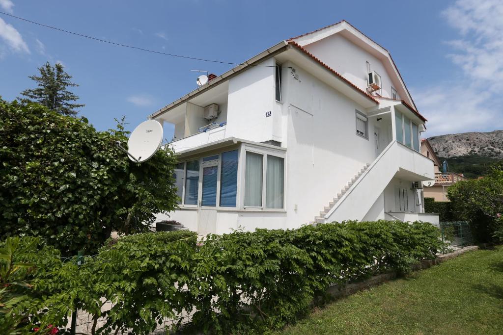 a white house with bushes in front of it at Apartments Ljubica in Baška