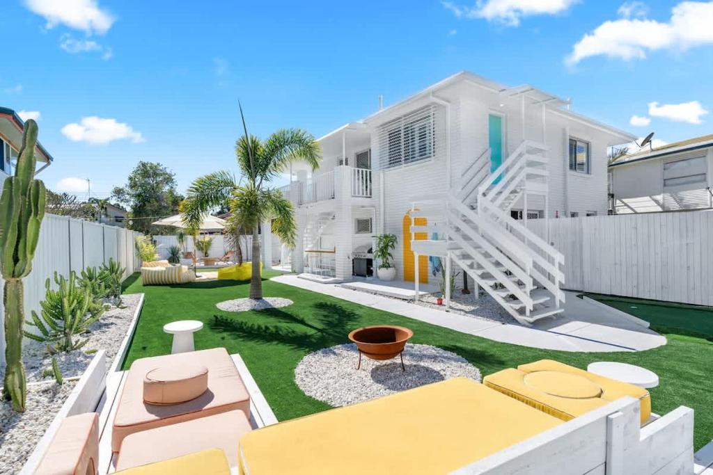a white house with a yard with yellow furniture at The Springs Villa 1 in Urangan