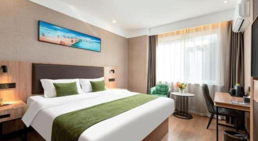 a hotel room with a large bed and a desk at Shell Hotel Shandong Jinan Daming Lake in Jinan