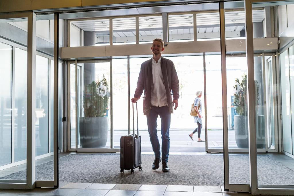 um homem a andar por um aeroporto com uma mala em ProfilHotels Mercur em Copenhaga