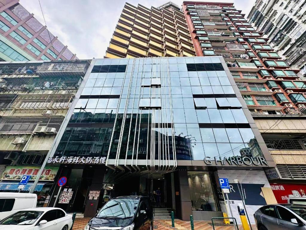 a tall glass building with cars parked in front of it at Grand Harbour Hotel in Macau