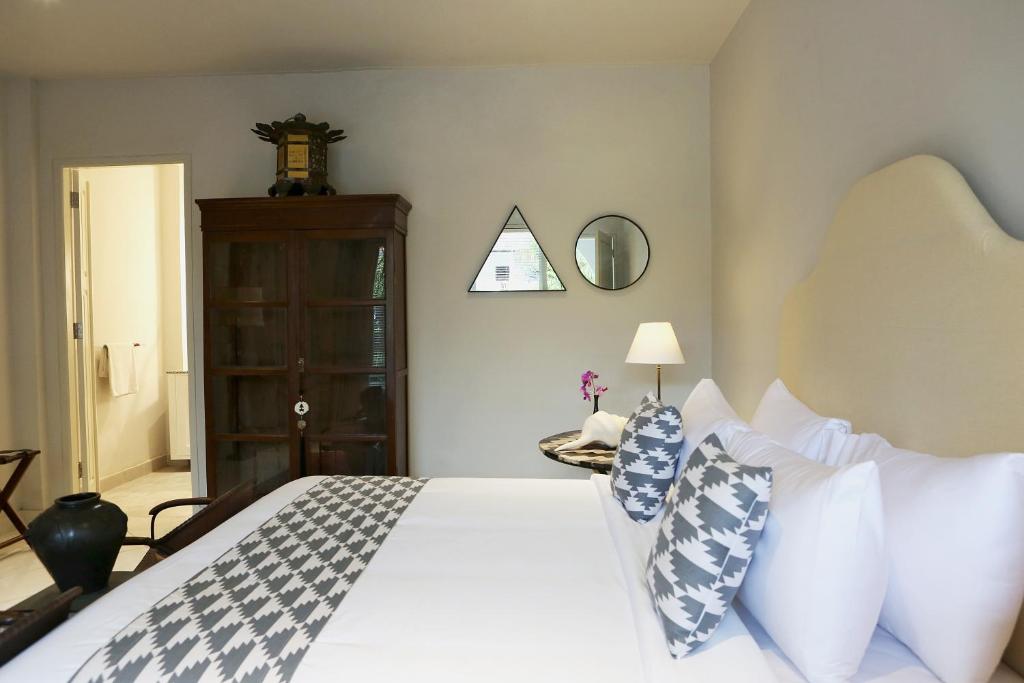 Un dormitorio con una cama blanca con almohadas azules y blancas en Room Sweet Room, Seminyak, en Seminyak