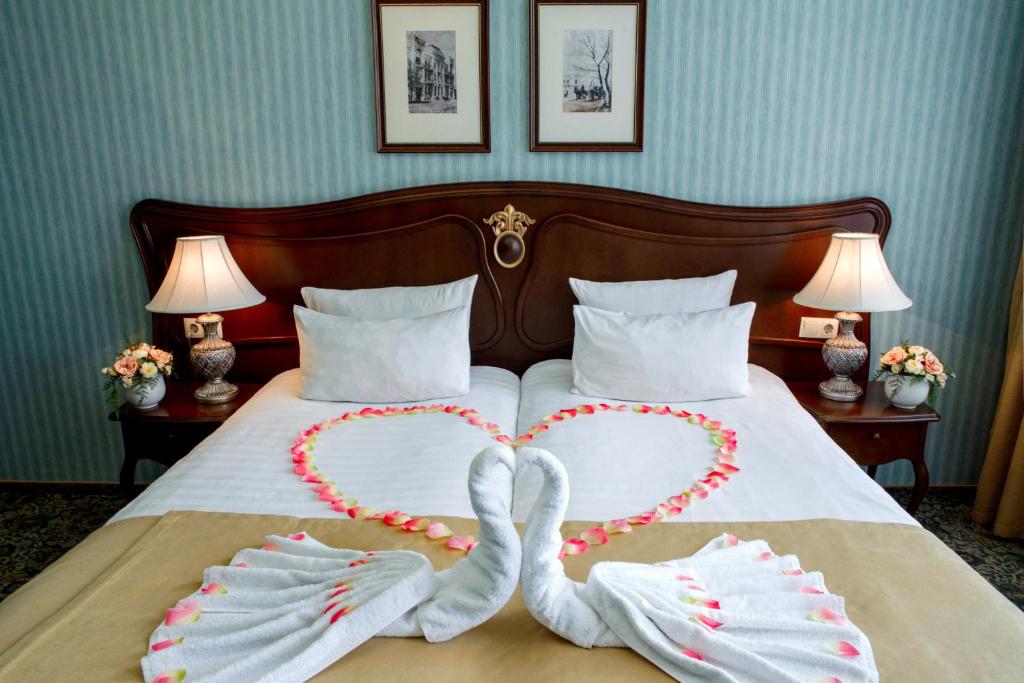 Dos cisnes haciendo forma de corazón en una cama en Hotel Zentralnaya, en Troitsk