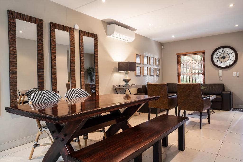 a dining room with a table and chairs and a clock at Avemore Mareba Court No 9 in Stellenbosch