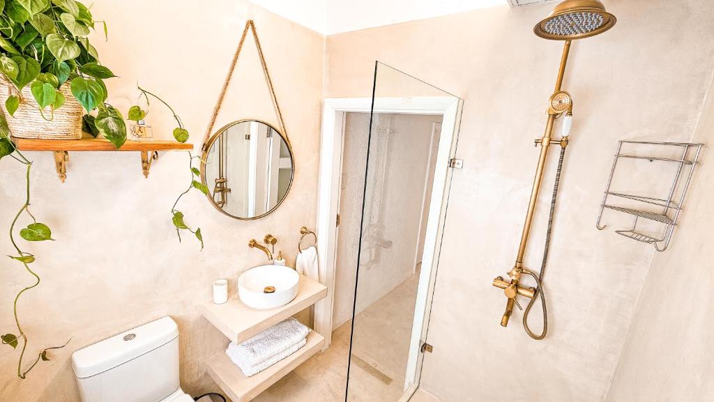 een badkamer met douche, toilet en spiegel bij Bali Beach Flats, Muizenberg in Kaapstad