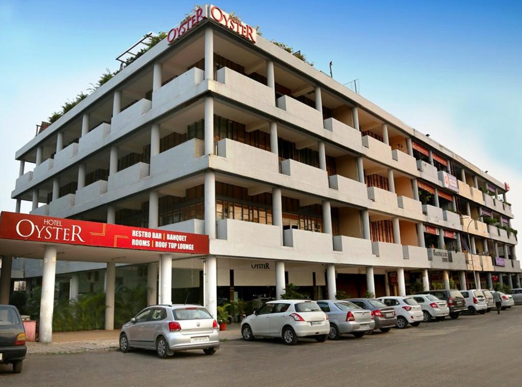 ein großes Gebäude mit Autos auf einem Parkplatz in der Unterkunft Hotel Oyster in Chandīgarh