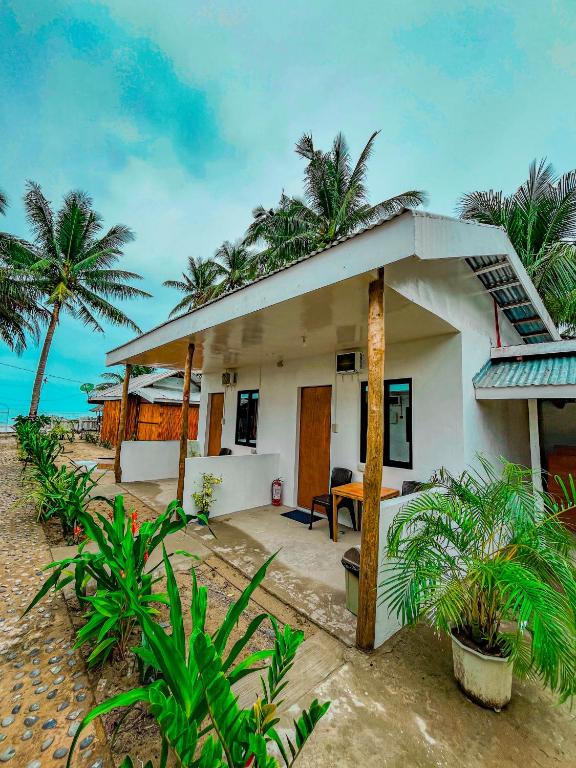 a small white house on the beach with palm trees at Jasmine Inn at Bucana Beach El Nido in El Nido