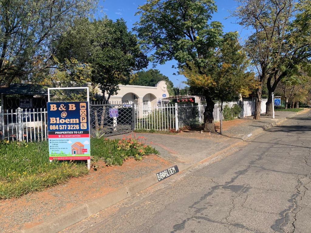 a sign on the side of a street next to a fence at B&B at Bloem in Bloemfontein