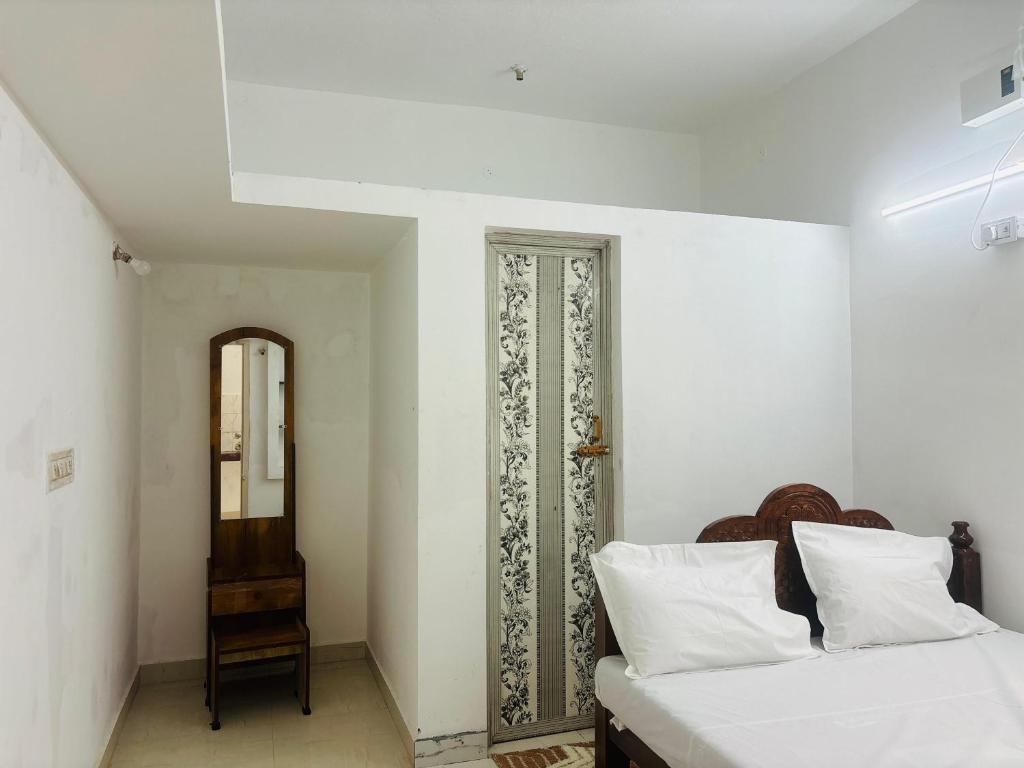 a white bedroom with a bed and a mirror at Chendur kumaran residency in Tiruchchendūr