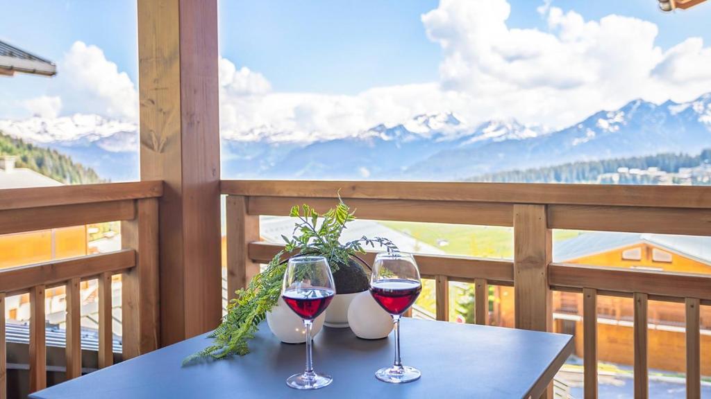 two glasses of wine sitting on a table on a balcony at ASAI210-7-1 Appartement 4 étoiles - Les Saisies - 8 personnes in Les Saisies