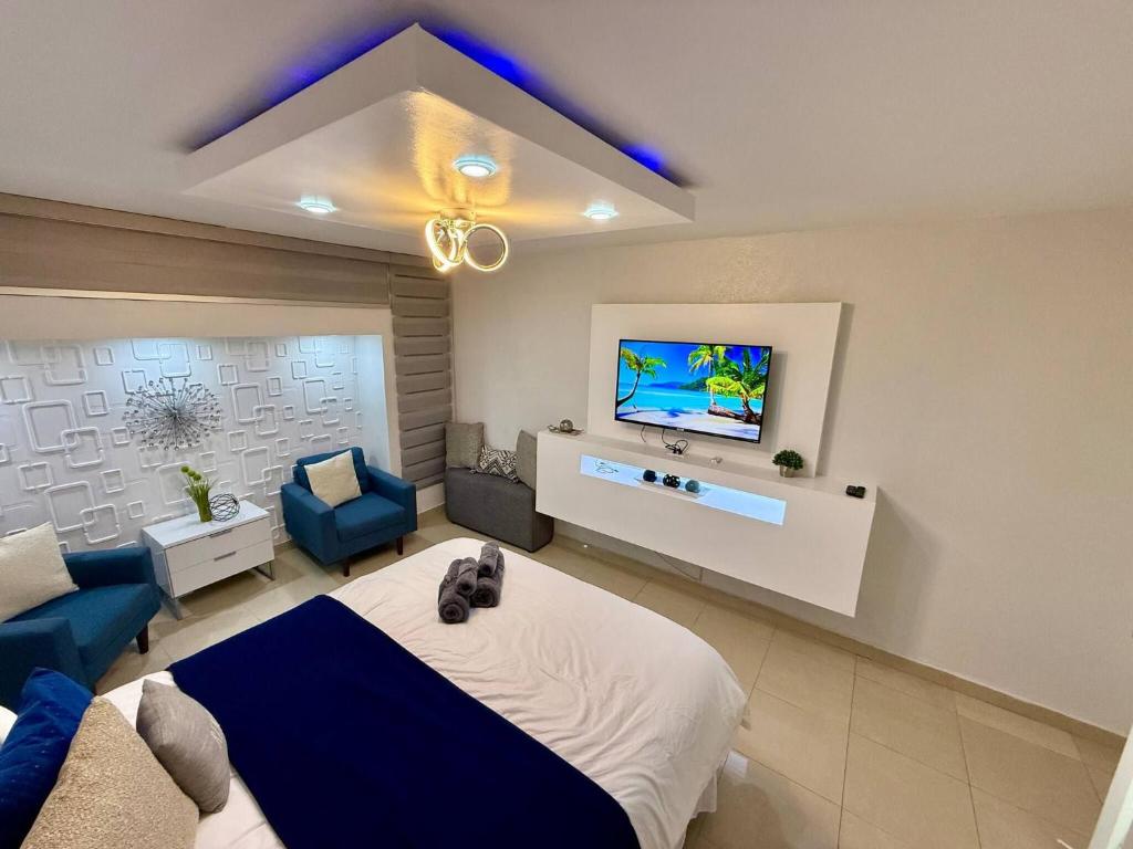 Un dormitorio con una cama y un televisor en la pared. en Isla Verde Beachfront Retreat with parking, en San Juan