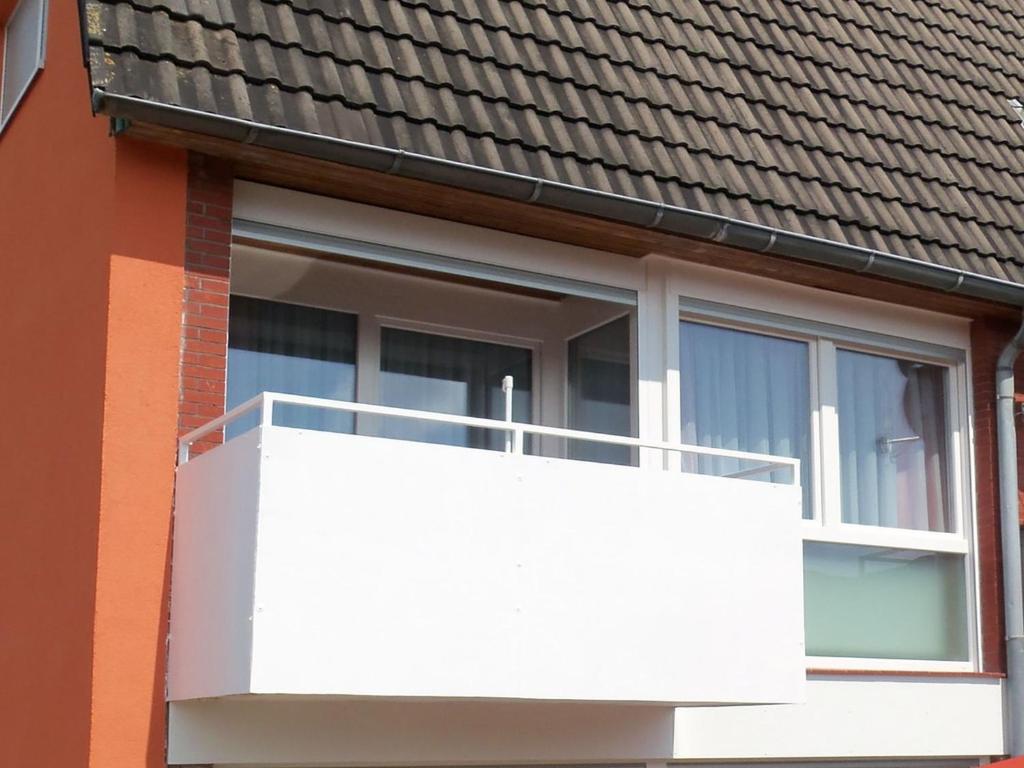 uma varanda branca ao lado de uma casa em Ferienwohnung Kapitein em Hooksiel