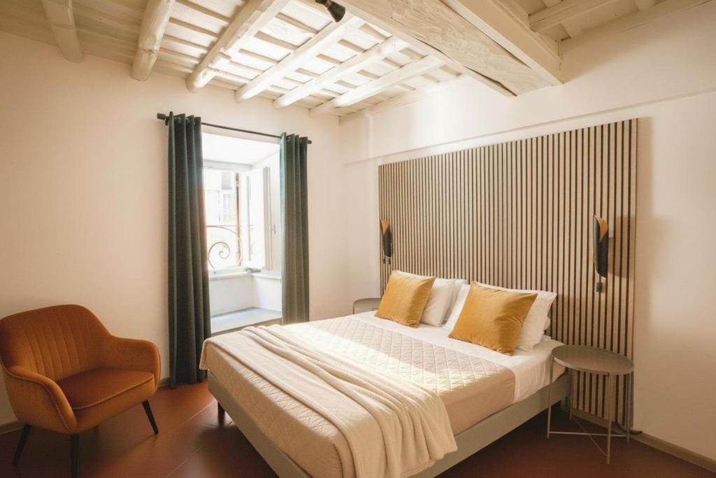 a bedroom with a bed and a chair and a window at Le Clarisse Pigna Apartment in Rome