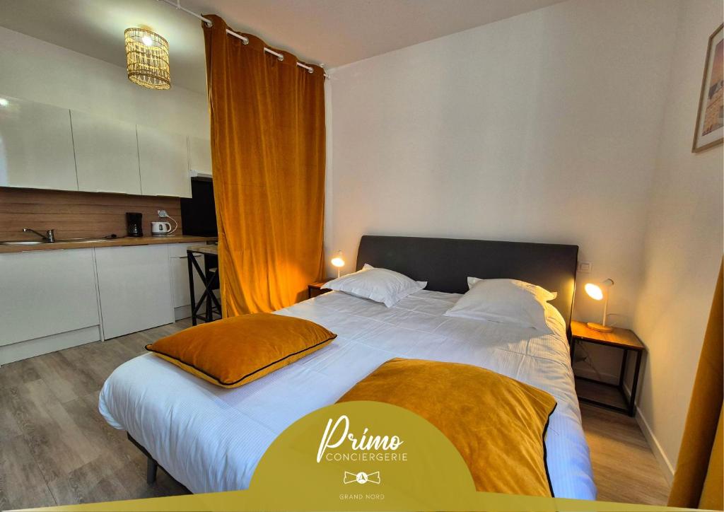 a bedroom with a large bed and a kitchen at Les Loges du Beffroi - L'éclatant in Arras