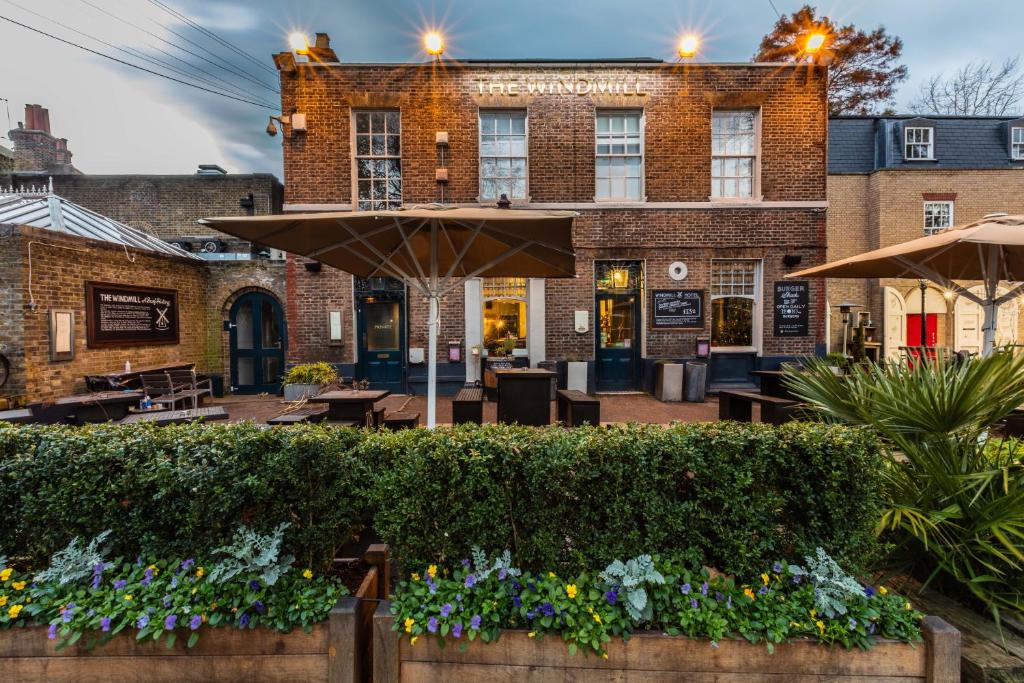 um restaurante com um guarda-chuva em frente a um edifício em The Windmill On The Common em Londres