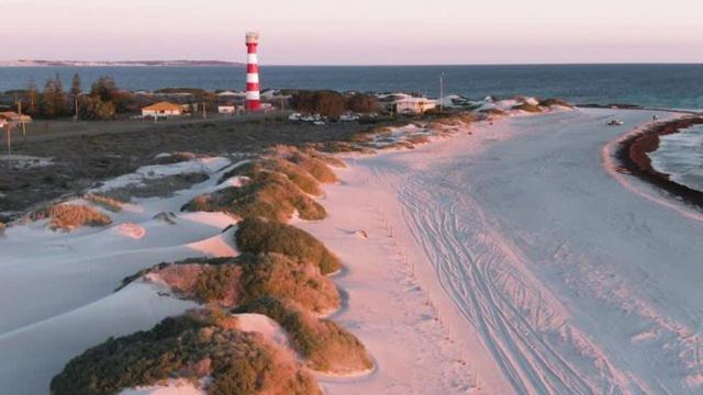 ジェラルトンにあるCharming West End Perfect for Workers & Touristsの遠くに灯台が見える雪の降るビーチ