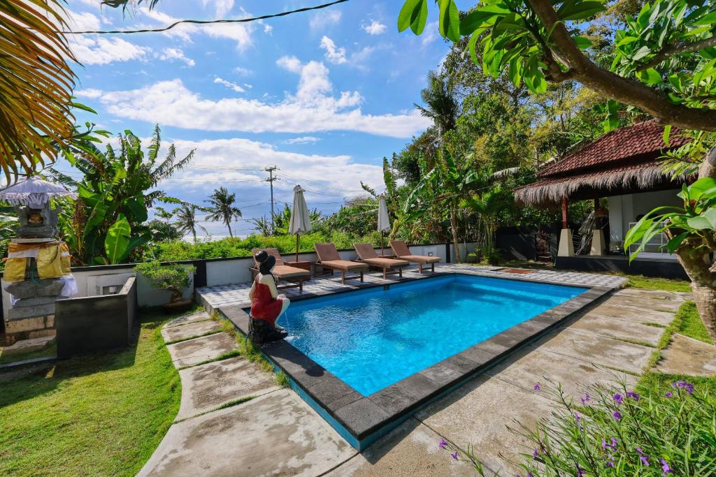 ein Kind, das neben einem Swimmingpool in einer Villa sitzt in der Unterkunft The Mandala Cottage in Nusa Penida
