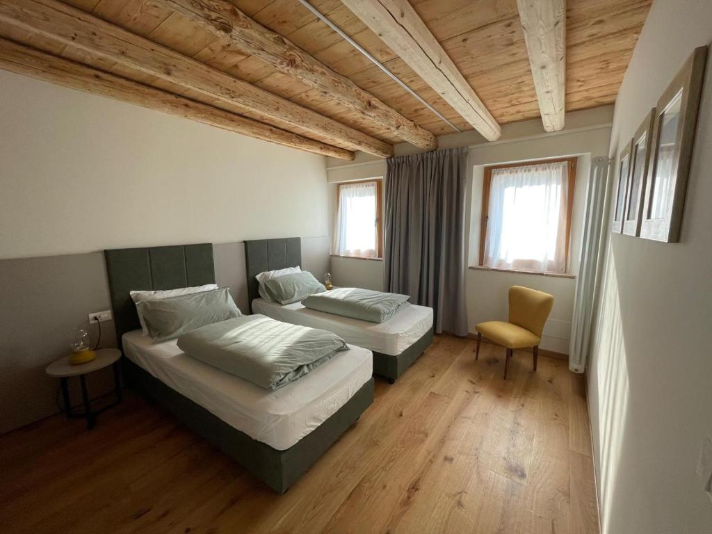 Una habitación con dos camas y una silla dentro. en Agriturismo I Giardini di Ron, en Valdobbiadene