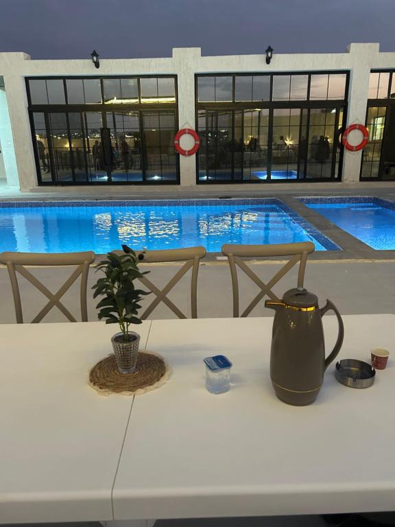 a table with a vase on it in front of a swimming pool at olive tree farm and chalet - مزرعه و شاليه شجره الزيتون 
