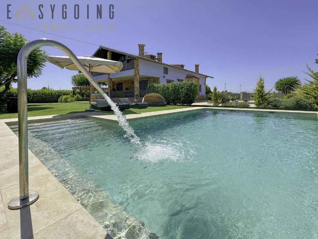 a swimming pool with a fountain in front of a house at Blue Wellness Villa in Elche