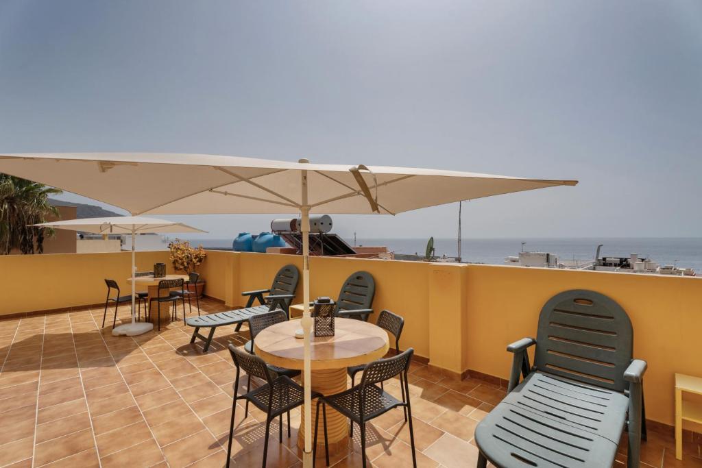 a patio with tables and chairs and an umbrella at Loft Pension Candelaria in Valle Gran Rey