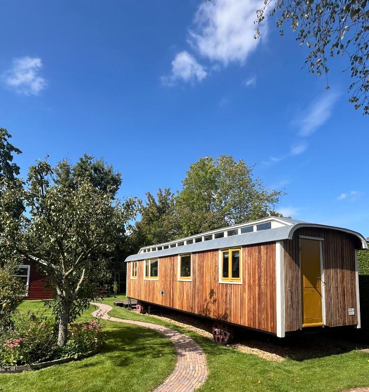 a wooden cabin in a yard with a tree at Sfeervolle, historische woonwagen en extra studio in ruime tuin in Rohel